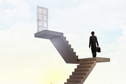 Businessman walking up staircase to door in sky