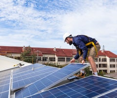 Solar panel technician installing solar panels on roof