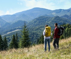 Couple with backpacks enjoying mountain landscape on sunny day