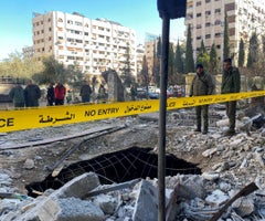 Oficiales de policía se paran sobre los escombros de un edificio dañado en el lugar de un ataque con cohetes, en el barrio de Kafr Sousa, en el centro de Damasco