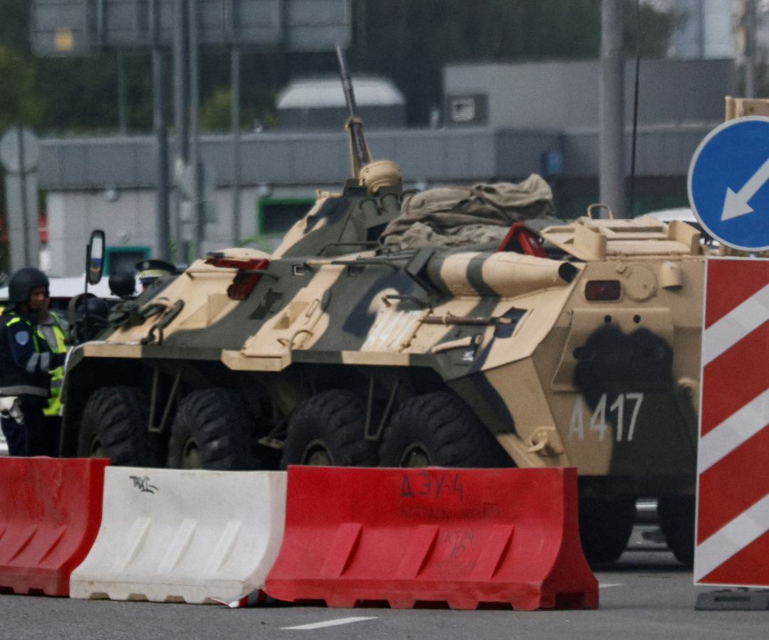 Un agente de la policía de tráfico controla un coche junto a un vehículo blindado de transporte de tropas en Moscú.