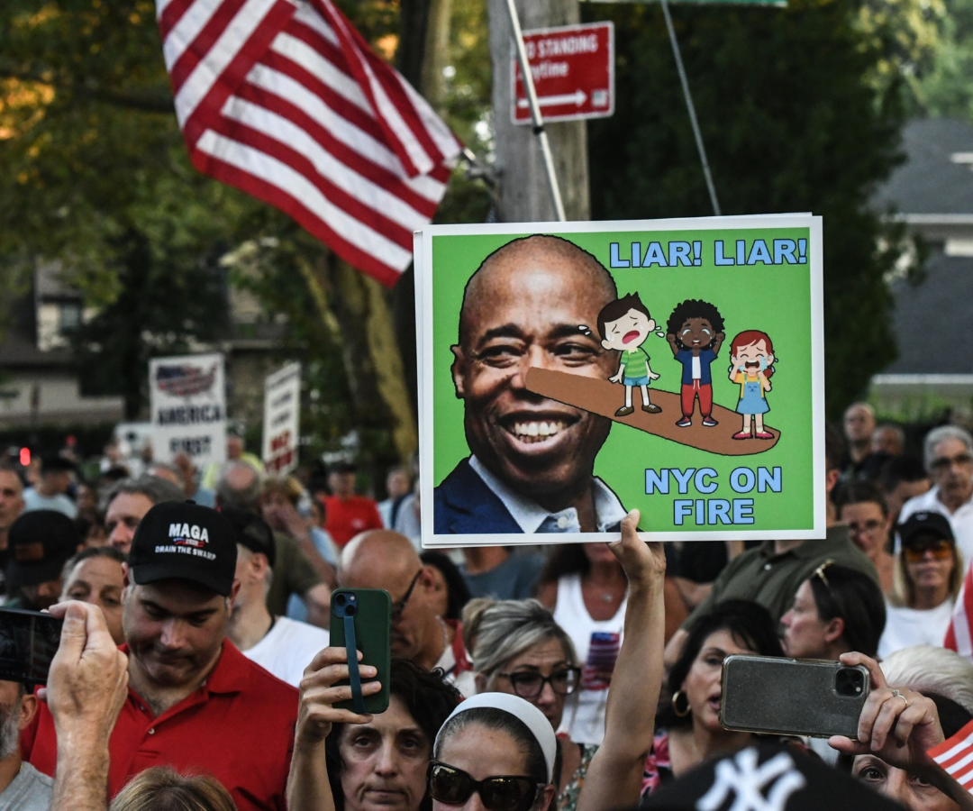 Un manifestante sostiene un cartel con la imagen del alcalde de Nueva York, Eric Adams, durante una concentración en protesta por la apertura de un centro de acogida temporal para solicitantes de asilo 