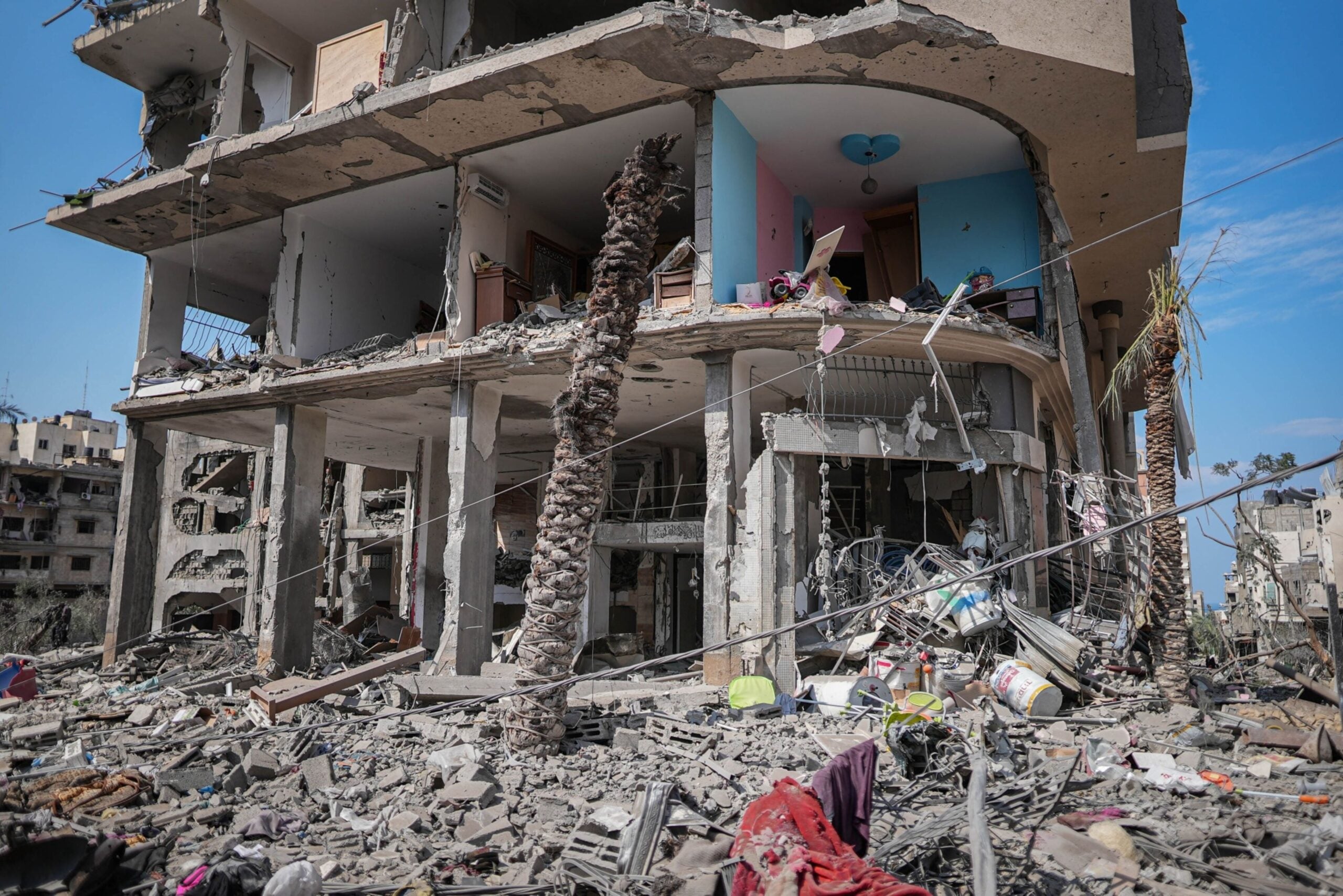 Los escombros cubren una calle junto a un edificio residencial destruido tras un ataque aéreo israelí en el barrio de Al-Karama, al norte de la ciudad de Gaza