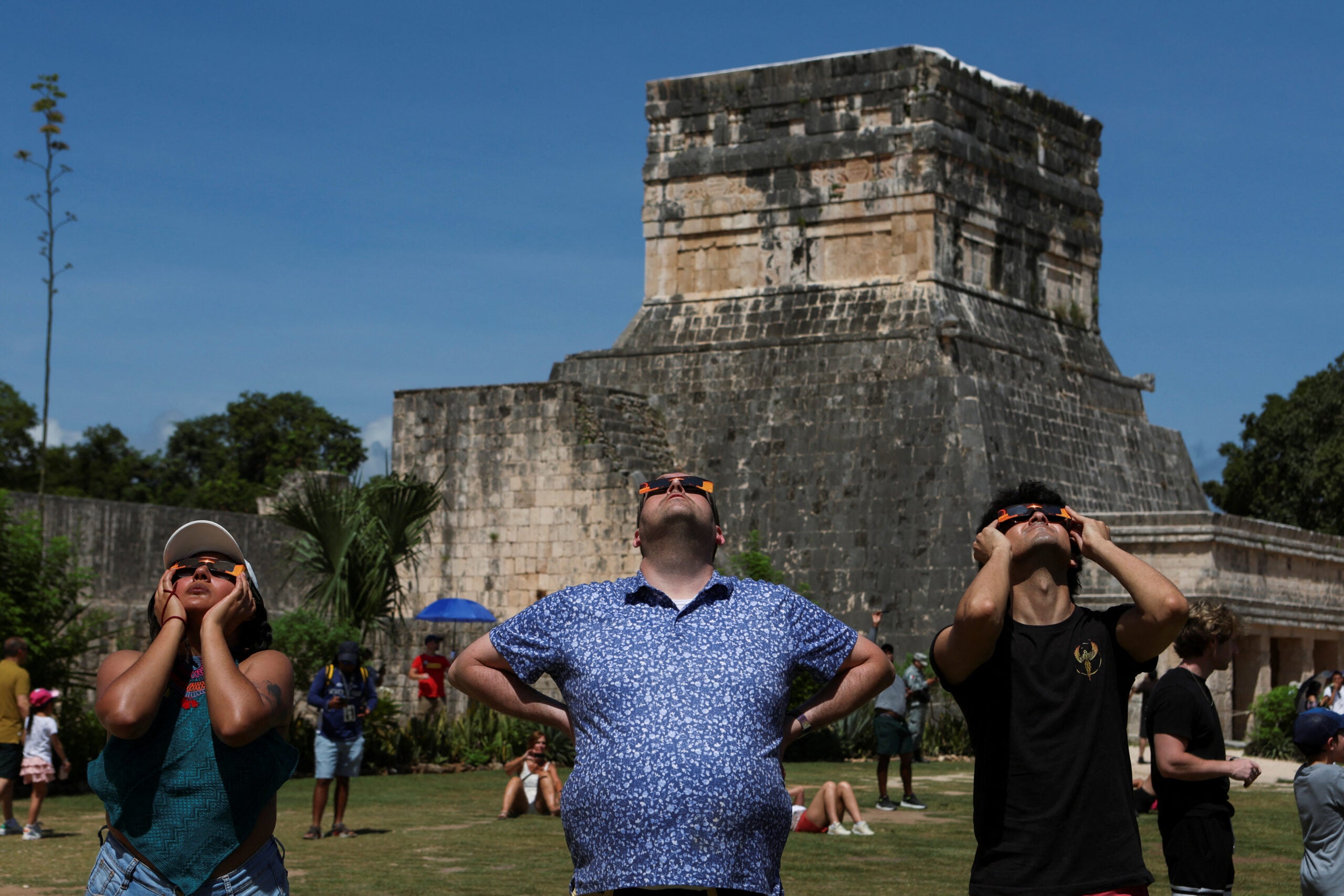 La gente usa gafas de soldadura para observar el eclipse solar en la zona arqueológica de Chichén Itzá, en Piste, México
