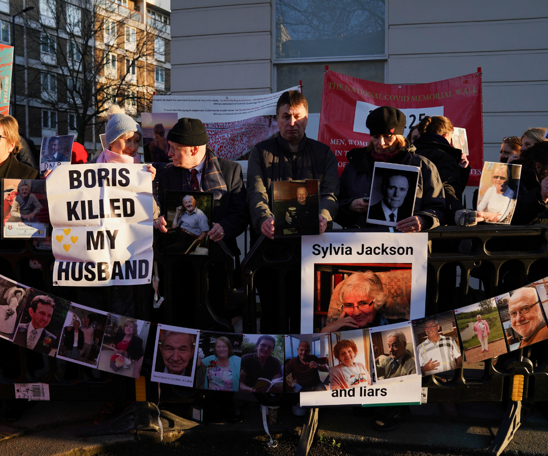 Manifestantes sostienen fotos y pancartas mientras esperan en el exterior de la investigación covid-19 del Reino Unido, donde el ex primer ministro británico Boris Johnson está prestando declaración, en Londres.