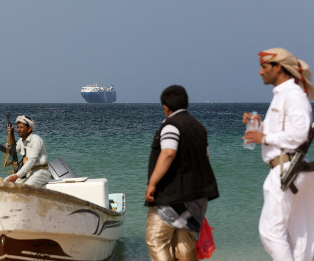 Hombres armados permanecen en la playa mientras el buque comercial Galaxy Leader, incautado por los hutíes de Yemen el mes pasado, está anclado frente a la costa de Al Salif.