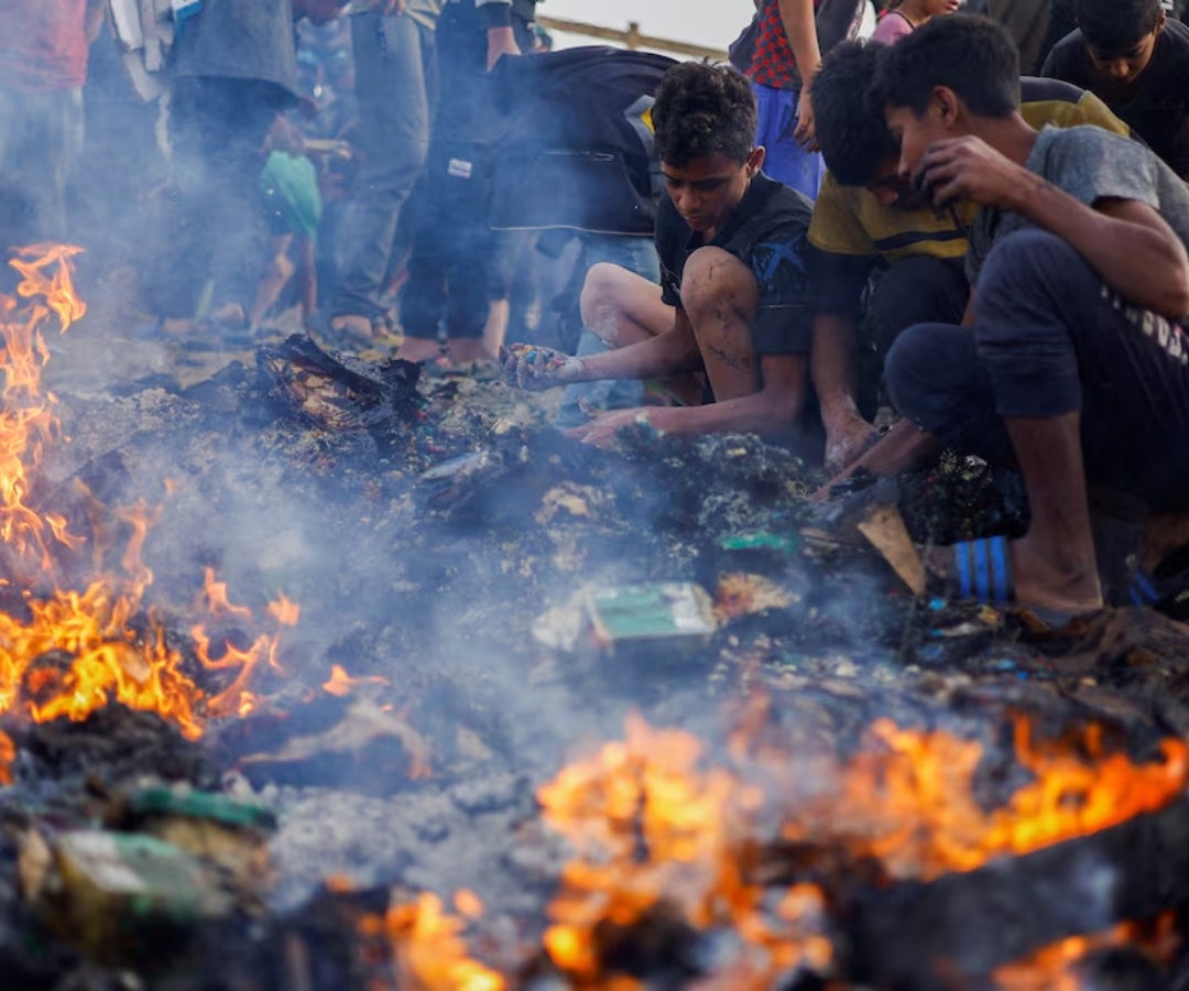 Palestinos buscan comida entre los escombros quemados tras un ataque israelí contra una zona designada para desplazados, en Rafah, en el sur de la Franja de Gaza.