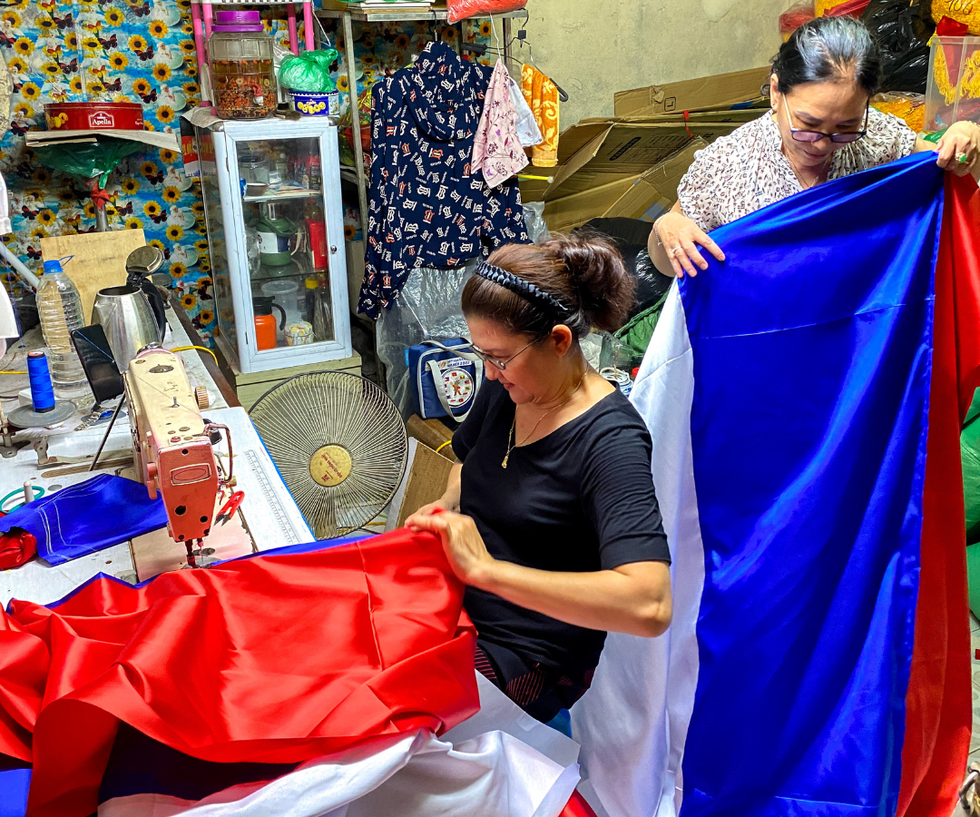 Le Kim Phuong, de 60 años, y Le Thu Hong, de 62, preparan banderas nacionales rusas antes de la visita del presidente ruso Putin a Vietnam, en Hanoi.
