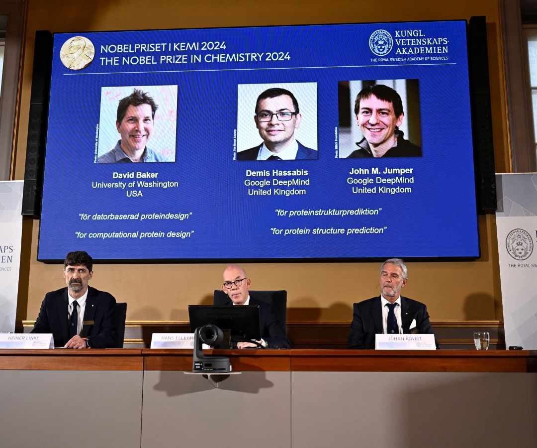 El colegiado que anunció el Nobel de Química mientras se muestran las imágenes de los ganadores, David Baker (Universidad de Washington, EE.UU.), Demis Hassabis (Google DeepMind, Reino Unido) y John M Jumper (Google DeepMind, Reino Unido), en Estocolmo.