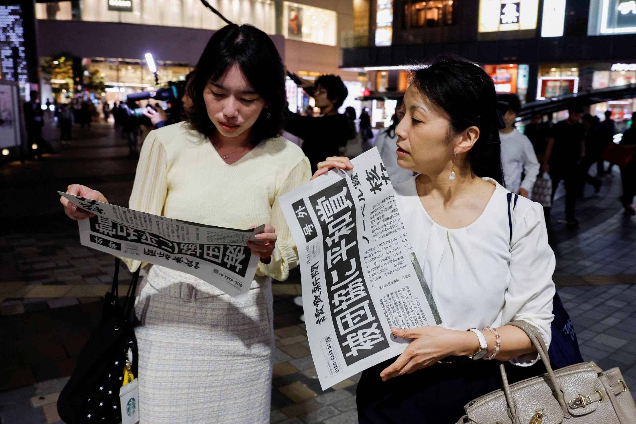 Japoneses reaccionan al recibir una edición extra del periódico Yomiuri con el anunció del premio Nobel para la organización Nihon Hidankyo
