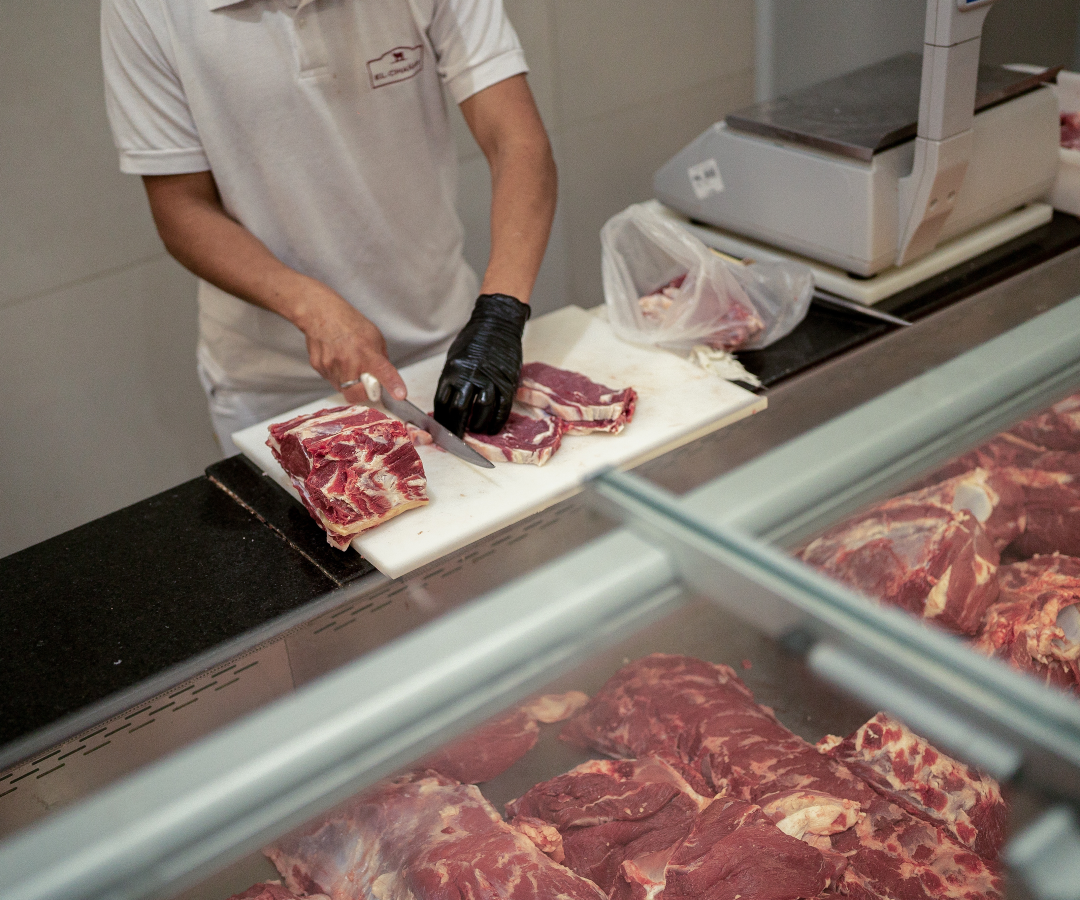 Un trabajador prepara un trozo de carne de res en una carnicería