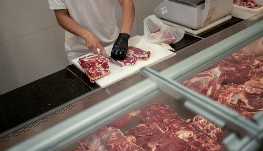 Un trabajador prepara un trozo de carne de res en una carnicería