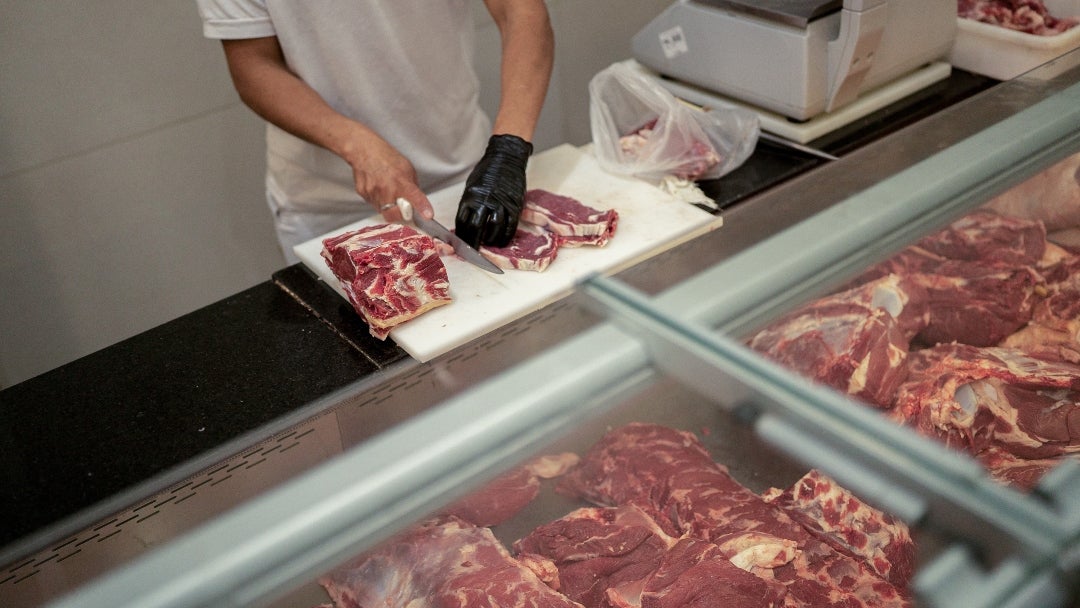 Un trabajador prepara un trozo de carne de res en una carnicería