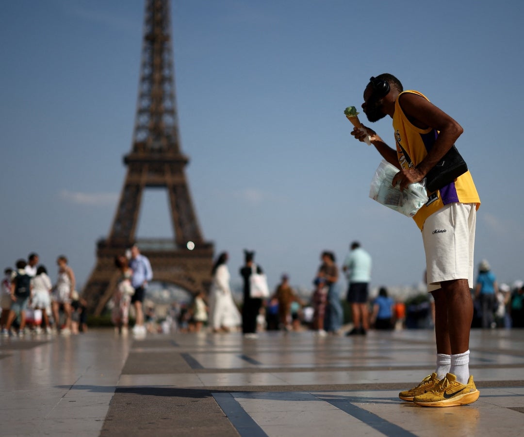 Una persona come un helado frente a la Torre Eiffel durante una ola de calor en París